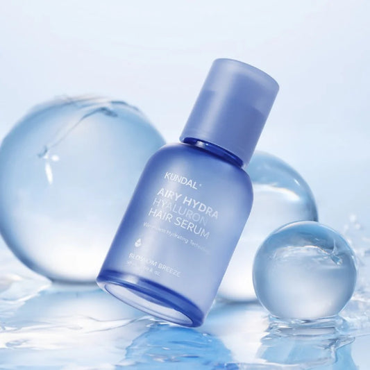 Kundal Airy Hydra Hyaluron Hair Serum bottle with water droplets on a light blue background