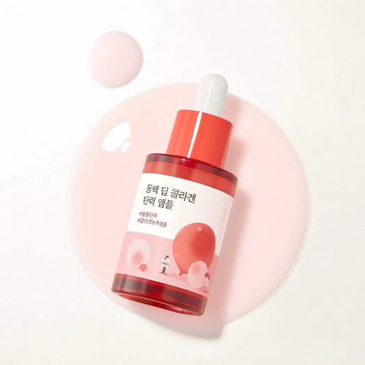 Red skincare serum bottle with a white cap on a light pink background