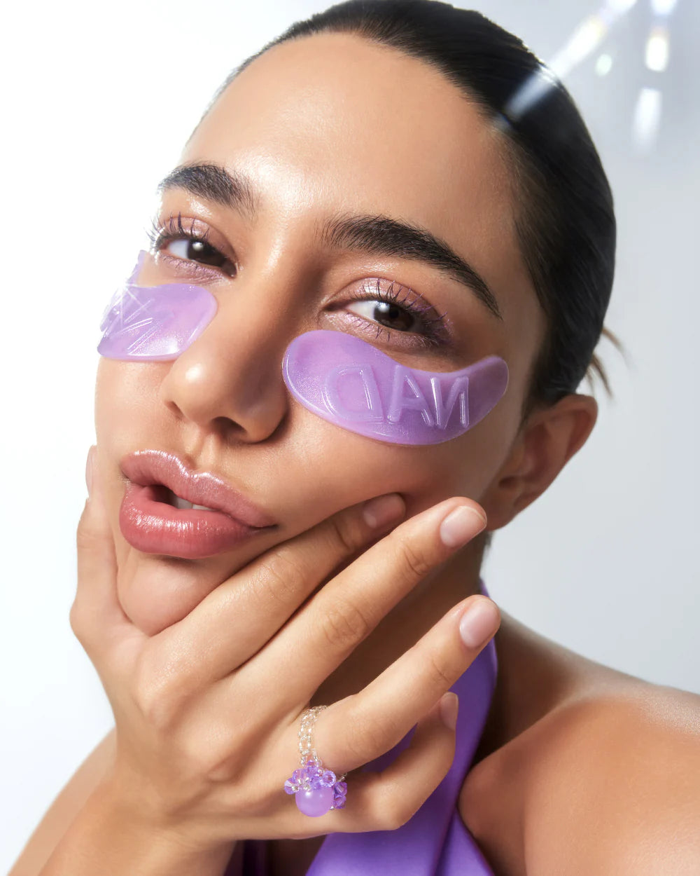 Woman wearing purple eye masks with a neutral background