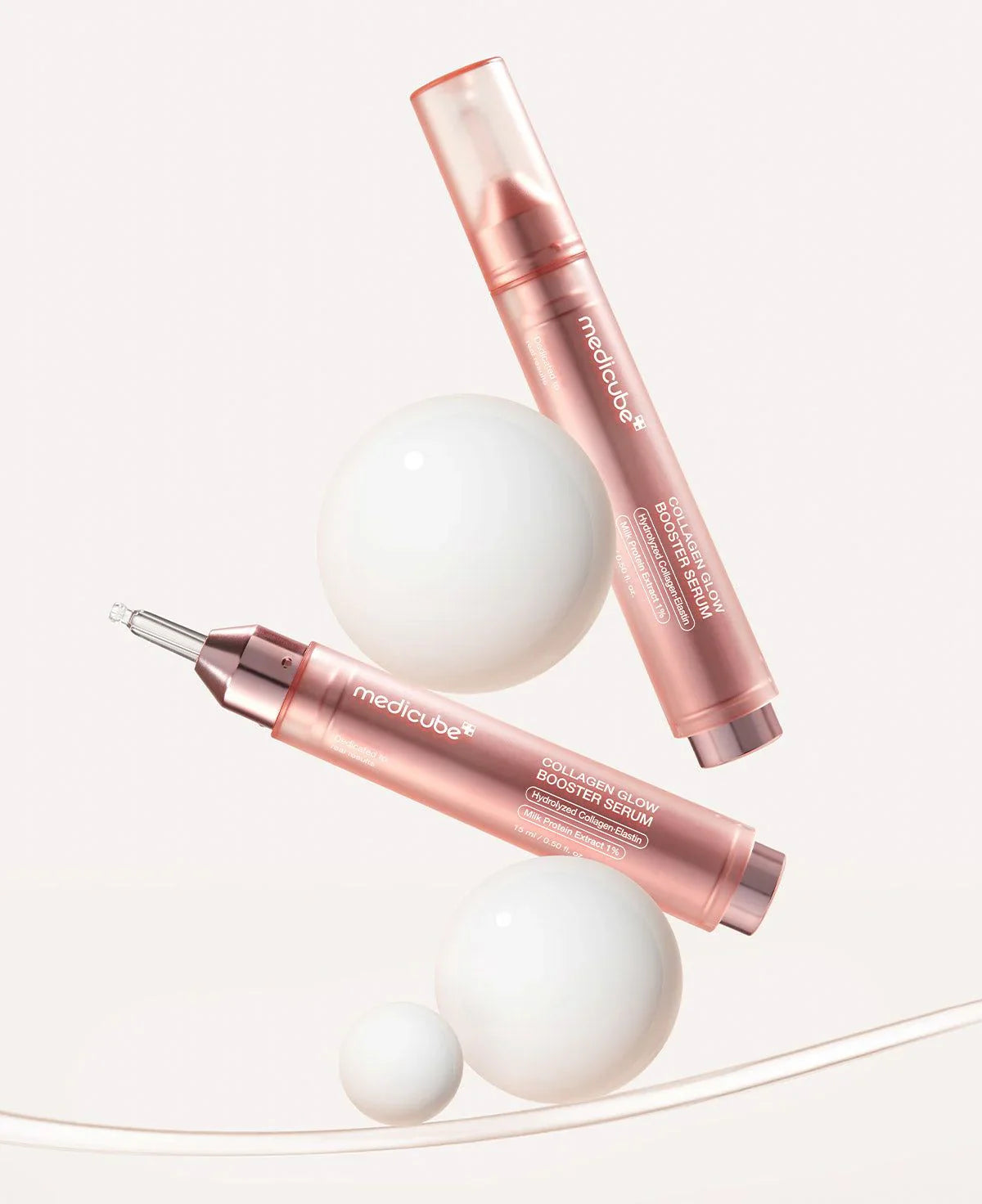 Two rose gold skincare products with applicators on a white background