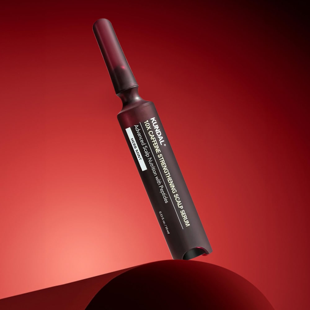 Kundal scalp serum bottle on a red background